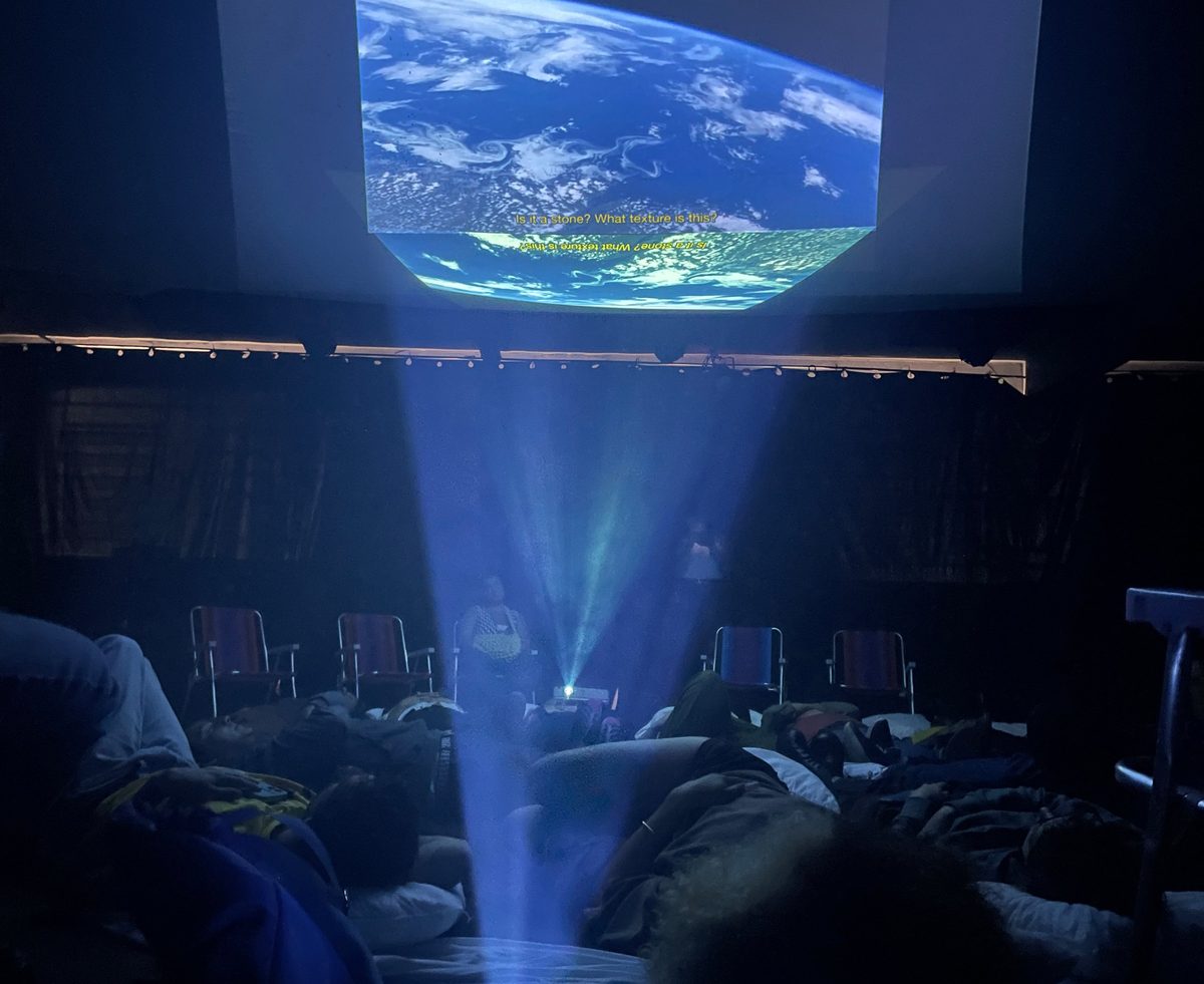 Imagem do planeta Terra projetada no teto, com o feixe do projetor atravessando a sala escura
